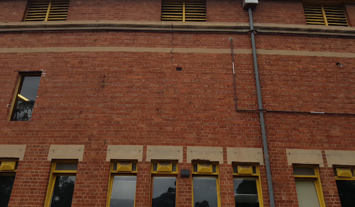 Red brick facade with a stepped vertical crack running between window openings