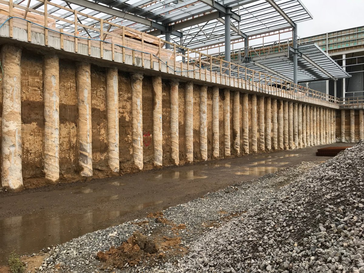 Exposed secant pile basement retaining wall beside a new steel-framed structure