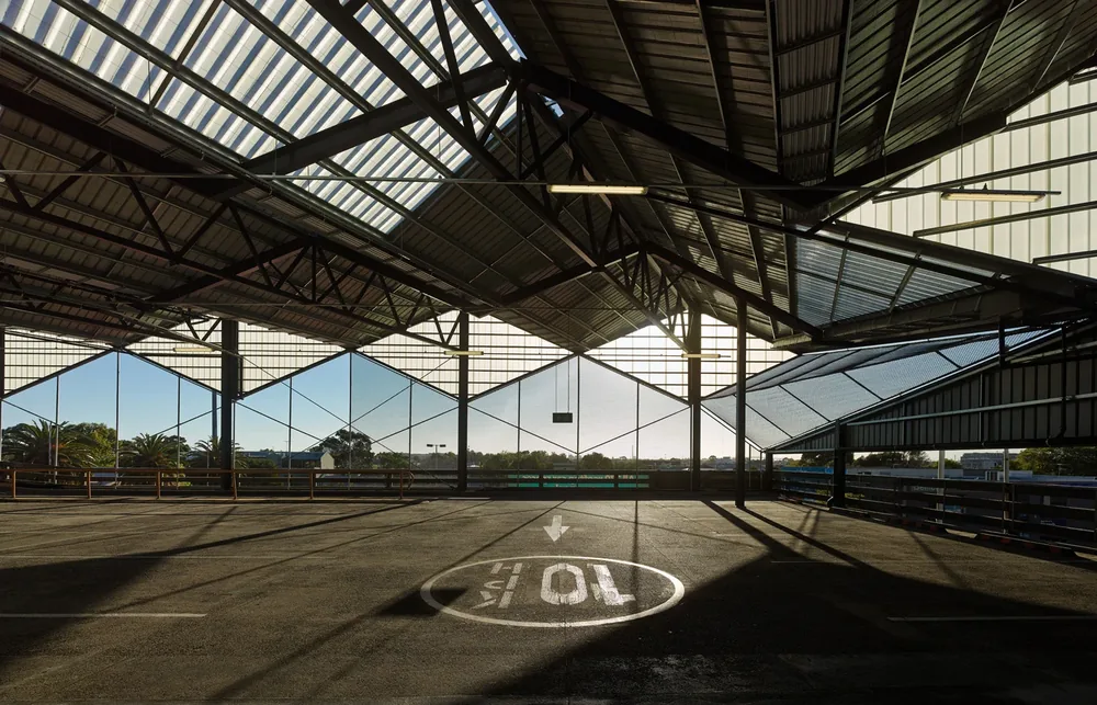 Interior view beneath the market's sawtooth roof showing exposed steel trusses, bracing and framing above the rooftop car park