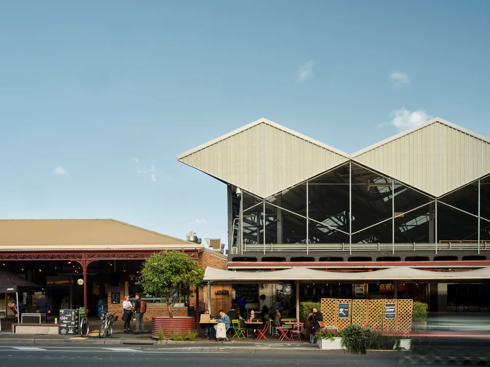 Street frontage of the market with people dining beneath the awning below the sawtooth roof structure