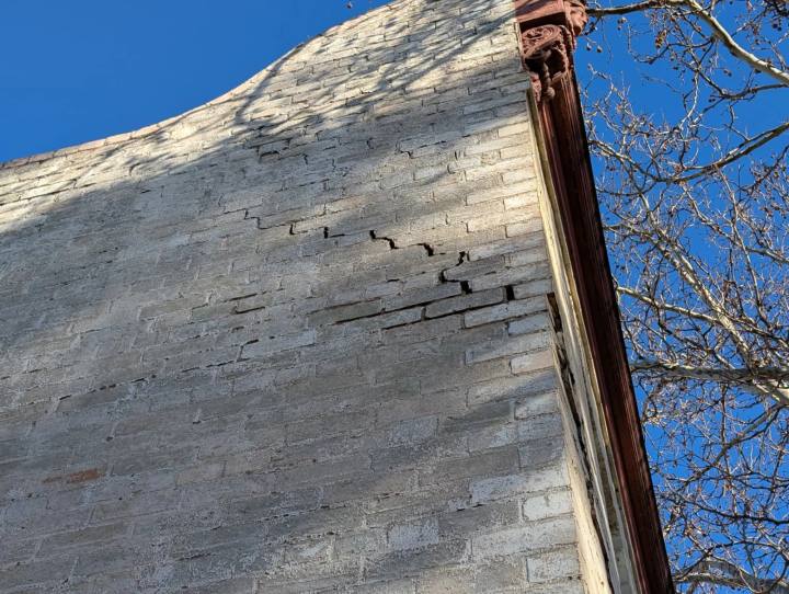Masonry wall with stair-step cracking, horizontal cracking and sideways wall movement near the parapet