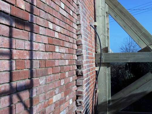 Bulging and displaced brickwork viewed along the face of a wall
