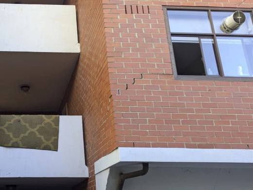 Stair-step cracking through the mortar joints of a brick wall below a window