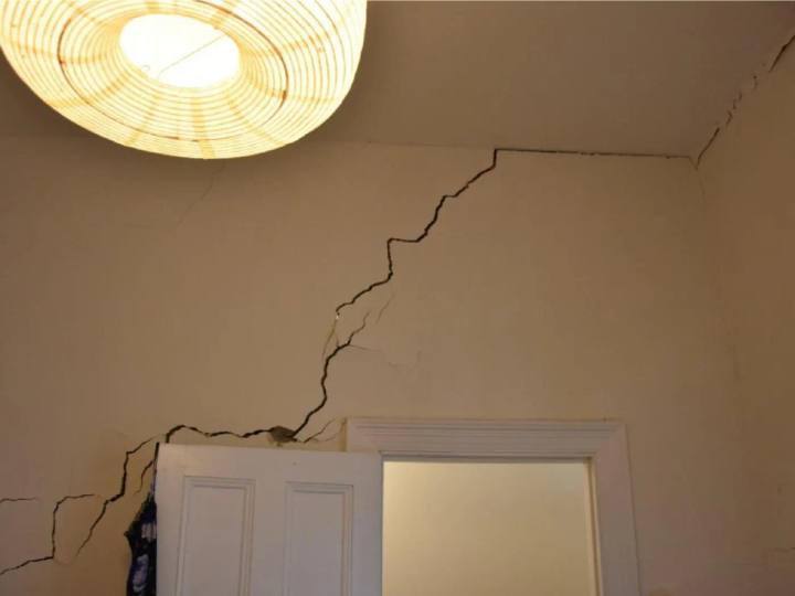 Cracking above a doorway extending across a wall and into the ceiling