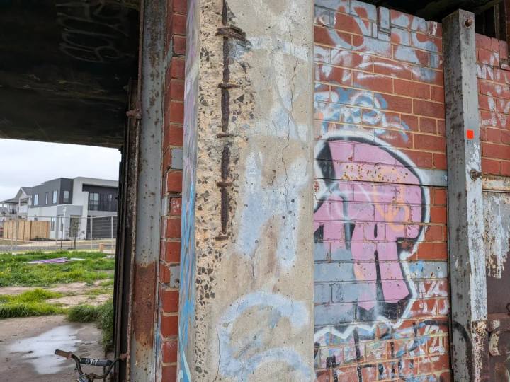 Corroded reinforcement exposed in a spalled concrete column with cracking through the surrounding concrete