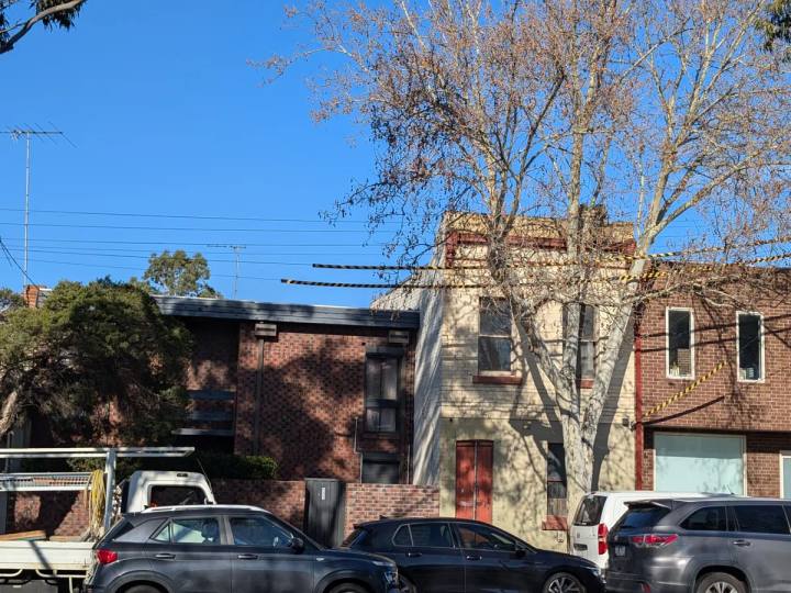 Large street tree growing close to a two-storey masonry building in Melbourne