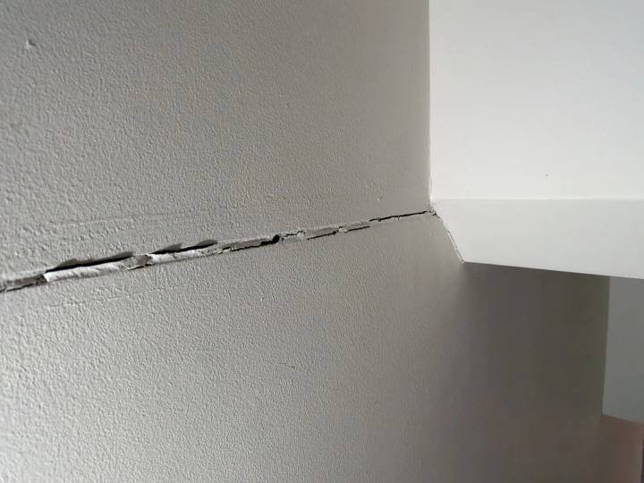 Horizontal crack running along a wall below the ceiling line