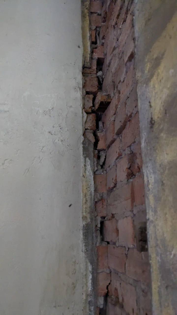Vertical crack opening through brickwork at a wall junction